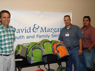 David and Margaret’s Executive Director Charles Rich accepts backpacks from Costco’s Samuel Weimer and Rick Teran. 