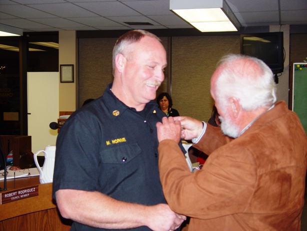 Roy Horine pins badge on his son Mark Horine, the city's new fire battalion chief.