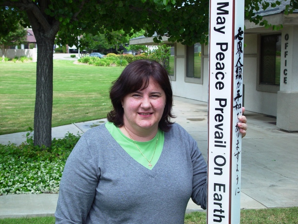 The Rev. Grace stands next to St. John's new Peace Pole. The cement was still wet. The inscription is in English, Japanese, Spanish and Aramaic.